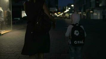 lento movimiento ver de mujer con hijo yendo en el noche vacío peatonal calle, rotterdam, Países Bajos video