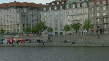 Visão a partir de barco comovente em a vltava rio ao longo residente hotel padrão e aterro, Praga, tcheco república video