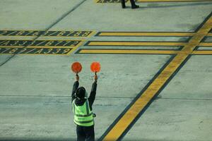 Bangkok, Thailand on July 9, 2023. Marshaller or aircraft parking attendant is the job of directing pilots to remove aircraft from the apron and park the aircraft after landing. photo