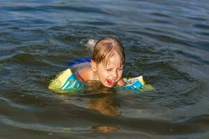 A happy child is swimming in the river on a very hot summer day. Swim in reservoirs. A happy family has fun and splashes in the water in the summer. photo