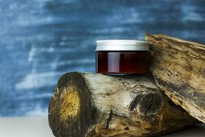 A jar of cream on the background of a dry stump and tree bark. Stylish appearance, layout, personality. Banner, a place for the text. photo