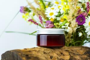 a jar of cream on the background of a dry stump, tree bark and a bouquet of wild flowers. Stylish appearance, layout, personality. Banner, a place for the text. photo