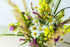 un ramo de flores de salvaje flores en un pequeño vaso florero en un blanco antecedentes. elegante apariencia, disposición, personalidad. bandera, un sitio para el texto foto