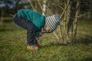 A funny boy walks through the spring park, examines the leaves with a large magnifying glass, looks for bugs and enjoys. photo