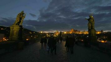 Tourists walk across Charles bridge in the evening in Prague video