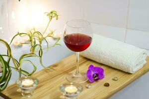 spa-salón de belleza, centro de bienestar. tratamiento de spa aromaterapia para el cuerpo femenino en el baño con una copa de vino, con velas, aceites y sal foto