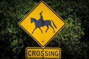 Square yellow Horse crossing sign is a warning sign. Drivers encountering a horse crossing sign should be alert for any people photo