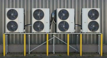 A series of split air conditioner condensers mounted on a building wall, showcasing modern cooling technology. photo