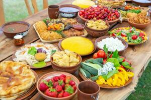 Homemade Romanian Food with grilled meat, polenta and vegetables Platter on camping. Romantic traditional moldavian food outside on the wood table. photo