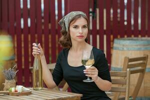 hermosa joven mujer Bebiendo blanco vino en el terraza de un restaurante foto