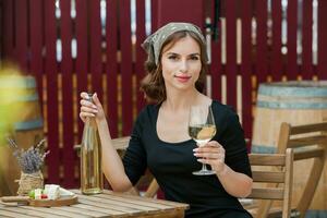 hermosa joven mujer Bebiendo blanco vino en el terraza de un restaurante foto