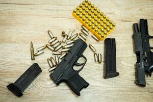 Handgun and bullets and mags lying on a wooden table photo