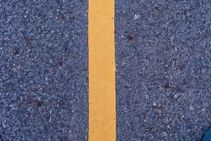 The concrete road surface has white and yellow road lines. photo