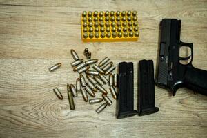 Handgun and bullets and mags lying on a wooden table photo