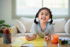 Cute little asian baby smiling painting with colorful paints using watercolor. Asian girl using paintbrush drawing color. Baby activity lifestyle concept. photo