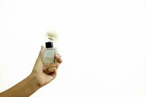 un mujer mano es participación un perfume botella. en un blanco antecedentes foto