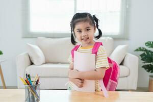 Asian kindergarten students smile backpack behind back a pink school bag and holding note book going to school for beginning of lessons. excited daughter are happy go school. Back to school concept. photo