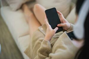 Top view. Asian woman wearing casual clothes sitting on a couch sofa using mobile phone to social media or search jobs or chatting or trade stock at the living room. photo