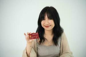 mujer sosteniendo mostrando tarjeta de crédito para comprar en línea. mujer asiática trabajando en casa. compras en línea, comercio electrónico, banca por Internet, gastar dinero, trabajar desde el concepto de hogar. foto