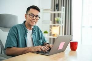 Smart Asian man smiling wearing glasses working with computer laptop. concept work form home, stay at home. freelance life style, New normal social distancing lifestyle. Work form anywhere concept. photo