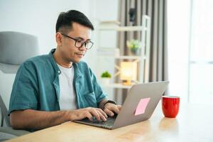 Smart Asian man smiling wearing glasses working with computer laptop. concept work form home, stay at home. freelance life style, New normal social distancing lifestyle. Work form anywhere concept. photo