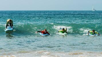 Group of young surfers at Carcavelos beach near Lisbon, Portugal during a summer day photo