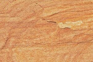 Natural rock texture. Stone grunge background. Light brown rough backdrop. Red ginger pattern. Fragment of mountain close-up. Rusty surface formation of wall with cracks and layer. Copy space for text photo