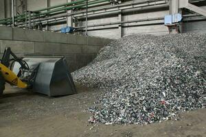 Shredded plastic pieces prepare for recycling. Raw cables material for reproduction. Sorting garbage on waste plant. Pile of scrap bottles on trash storage factory. Environmental concept photo