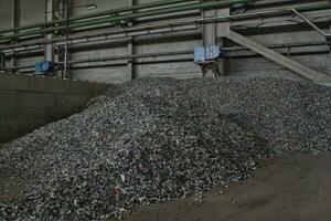 Shredded plastic pieces prepare for recycling. Raw cables material for reproduction. Sorting garbage on waste plant. Pile of scrap bottles on trash storage factory. Environmental concept photo