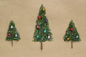 Green srpuce needles Christmas tree pattern with jingle bells on craft recycled paper. Ecological minimal design for holiday postcard. Eco friendly, zero waste, diy, nature concept. Flatlay, top view photo