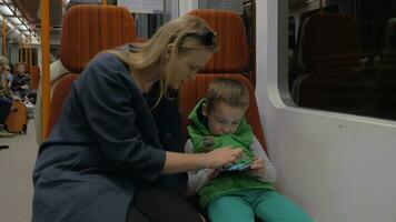 criança e mãe com Móvel telefone dentro metrô trem video