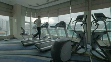 Woman working out on running machine and looking at city video