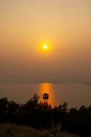 The river in Nakhon Ratchasima province where the sun is setting through the thick fog behind the mountains, giving rise to the orange color of the sun in the evening. photo