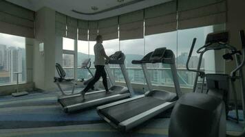 Clip of woman on the treadmill in fitness centre looking at window with cityscape Hong Kong, China video