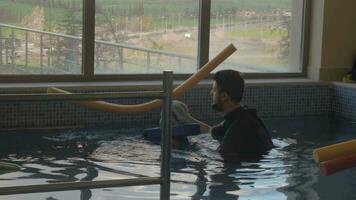 rehabilitación centrar evexia, nadando lección, pequeño chico y profesor en nadando piscina video