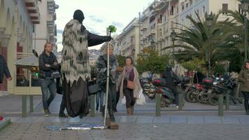 In sunny day a street performer in costume of death shows a trick how to fly in the air video