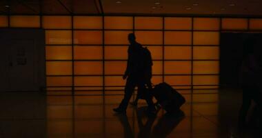 People with luggage in poor lighted corridor of airport terminal video