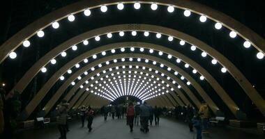 gens en marchant dans illuminé passerelle de parc sokolniki, Moscou video