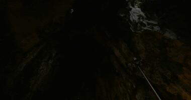 In Batu Caves seen cave with stalactite and walking tourists photographing on mobile phone landmark video