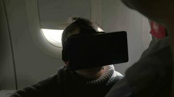 en avión se sienta un pequeño chico con virtual realidad lentes video