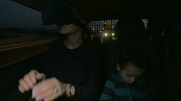 im ne Kallikratie, Griechenland im Auto Fahrten ein jung Mutter mit virtuell Wirklichkeit Brille und in der Nähe von Sitzung ihr wenig Sohn video