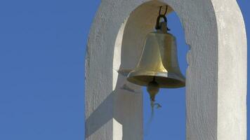 On a semicircular concrete arch hangs a bell and swinging in the wind video