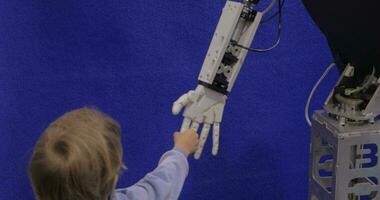 Close up view of boy hand holds white moving plastic hand of humanoid robot in Robotics exhibition in Moscow, Russia video