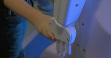 Close up view of boy hand holds white plastic hand of humanoid robot in Robotics exhibition in Moscow, Russia video