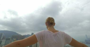 In Hong Kong, China on the terrace a young girl does exercises with dumbbells spreading hands video