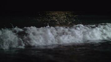 donker schuimend golven het wassen de kust Bij nacht video