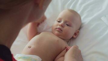 A mother playing with a 6 months old girl, who is lying on a bed video