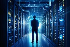 Rear view of businessman standing in server room and looking at data center photo