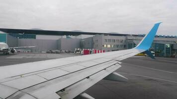 NOVOSIBIRSK, RUSSIA OCTOBER 02, 2022 - View of the taxiing aircraft wing against the backdrop of Tolmachevo Airport, Novosibirsk. Flight departure video