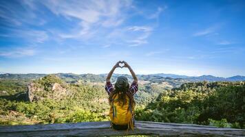 Young woman Tourists with backpacks Happy to travel She raised her hand to make a heart shape and enjoy the natural scenery on the mountain. photo